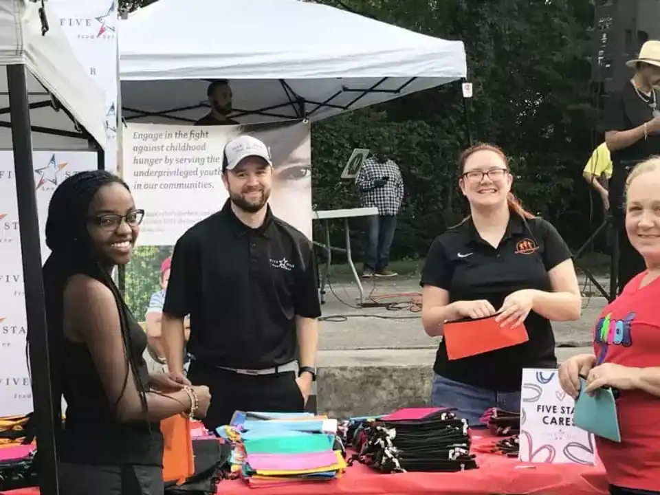 Five Star Food Service Employees handing out pencil bags to children