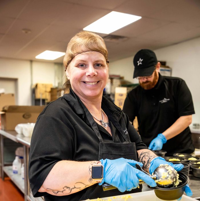 Five Star Food Service employee smiling as she prepares food