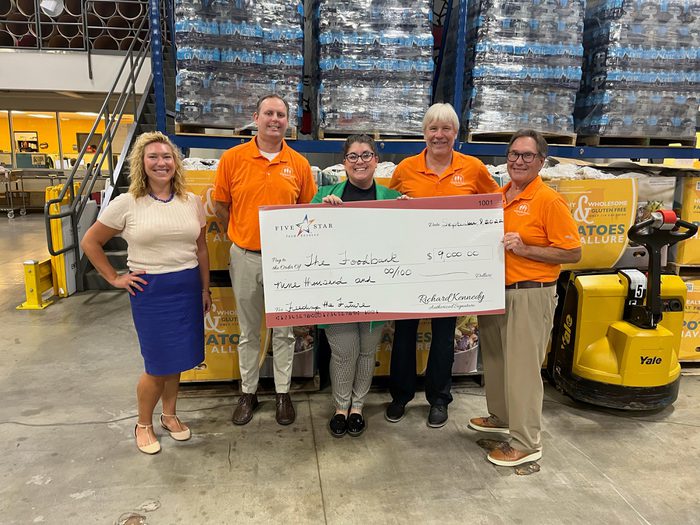 Five employees holding big check